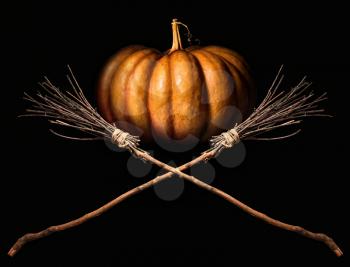 big orange pumpkin and two witches classic crossed brooms on a dark background