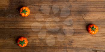 Three artificial pumpkins on a rough wooden background with place for your text. Top view.