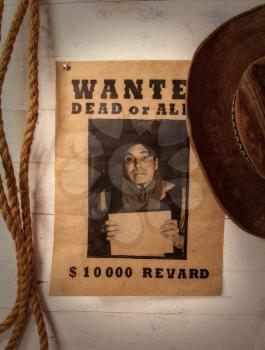 old paper announcement of criminal search and reward on yellowed paper pinned to a rough wooden wall