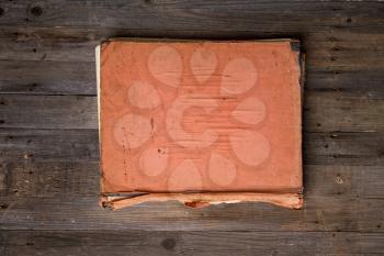 old closed book with blank cover without text on a rough wooden background
