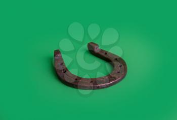 Steel rusty horseshoe luck symbol on a green background