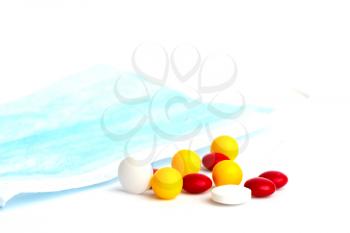 several pills of different shapes and colors and a medical mask isolated on white background