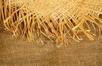 straw hat and rough burlap background closeup with place for text