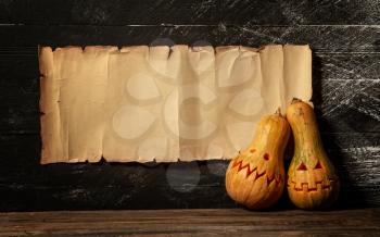 two festive Halloween pumpkins with different emotions on the background of a paper sheet with a place for text