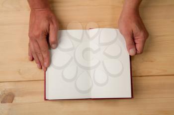 Male hands opened the page of a new book on a wooden background