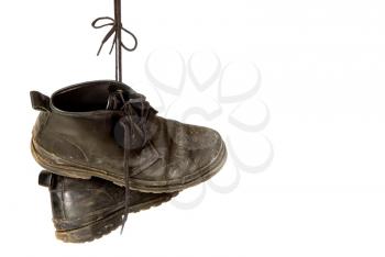 old shabby leather shoes hang on laces on a white background