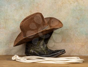 Shabby old ornate classic cowboy boots hat and lasso on vintage background