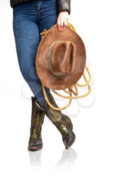 Female legs in leather cowboy boots and blue jeans with wide-brimmed hat and lasso isolated on white background
