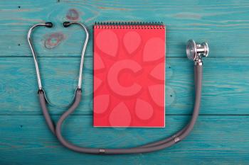 Workplace of doctor - stethoscope and notepad on wooden desk