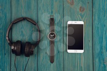 Smartphone, headphones and watch on the blue background