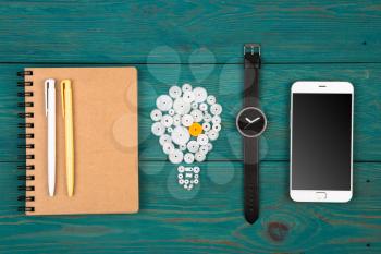 Business idea concept - bulb sign, notepad, watch and phone on the desk