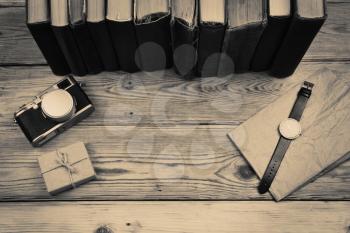wooden desktop with books, camera, watch and gift box in monochrome