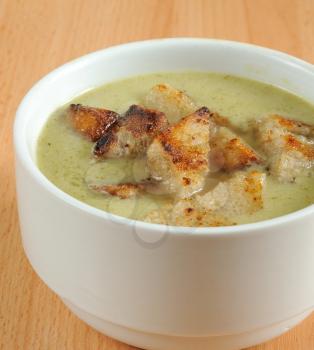 Close-up image of broccoli soup in white dish with crouton.
