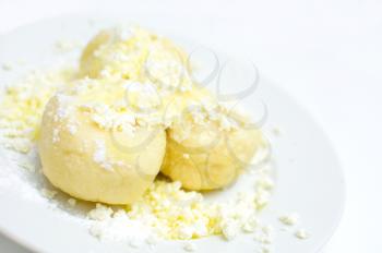 Fruit dumplings with fruit sprinkled with cheese, sugar and melted butter on white plate.