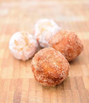 Fresh fried donuts powdered by a sugar on the wooden plate.