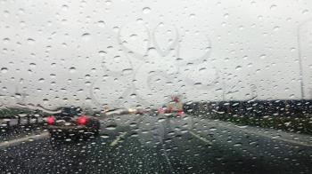 Driving the car on rainy highway. Interior view on wet glass. Point of view shot.
