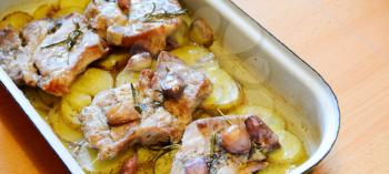 Roasted pork neck chops with potatoes slices, rosemary and garlic in pan. 