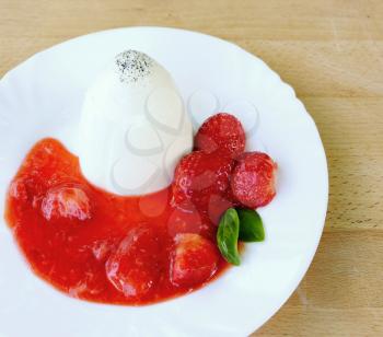 Panna Cotta with strawberries, strawberries sauce and basil leaves on white plate.