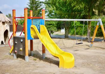Yellow slide and chain swings in the empty playground.