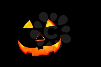 Illuminated Halloween smiling spooky pumpkin face on a dark background.