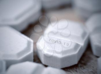 White pill with COVID-19 inscription, macro shot.