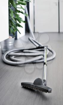 Central vacuum cleaner hose laid on the floor in the living room. Cleaning room conceptual shot, focused on foreground.