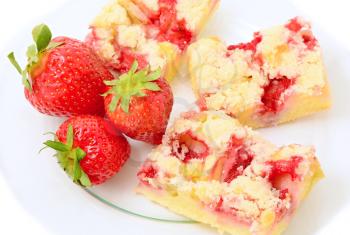 Sliced strawberry cakes with whole fresh strawberries on glass plate over white background.