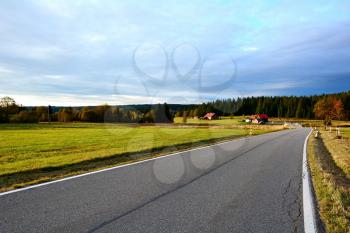 Country road near Kvilda village between meadows in Sumava National Park with beautiful sunset light. 