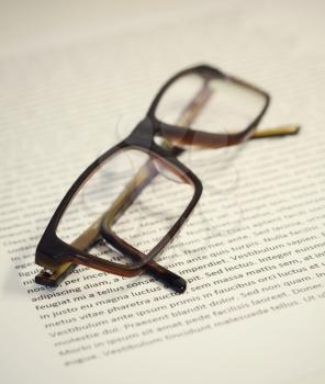 Closeup of folded eyeglasses on paper sheet with lorem ipsum text. 