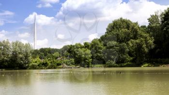 Landscape of bridge, trees, pond and white fluffy clouds
