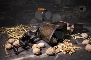 Walnuts and hand walnuts grinder on a wooden surface