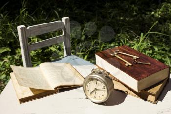 Vintage still life with old alarm clock, keys and books on a white wooden table