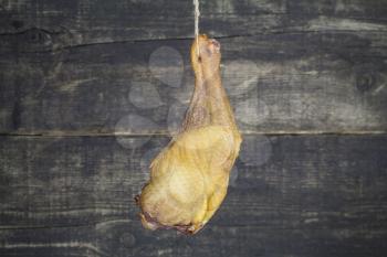 Smoked Chicken Leg Hanging on the Rope Against Wooden Background