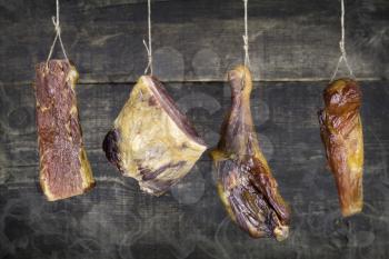 Smoked Meat Hanging on the Rope Against Wooden Background With Smoke