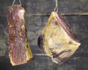 Smoked Pork Meat Hanging on the Rope Against Wooden Background
