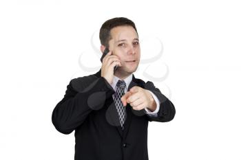 Businessman in Black Suit Talking On The Phone And Pointing Index Finger Towards Camera Against White Background