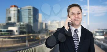 Businessman Talking On The Phone With Business City and Corporate Buildings In Background