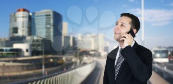 Businessman Talking On The Phone With Business City and Corporate Buildings In Background