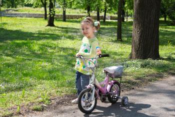 little girl with bicycle posing in park