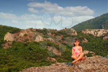 beautiful little girl sitting on mountain top 