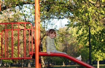 little girl sitting on playground slide