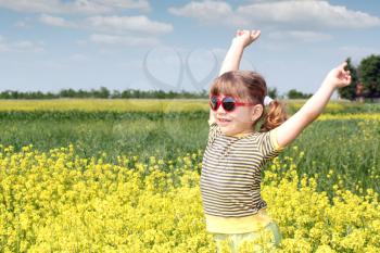 happy little girl standing in yellow flower field