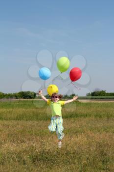 happy little girl with balloons jumping on field