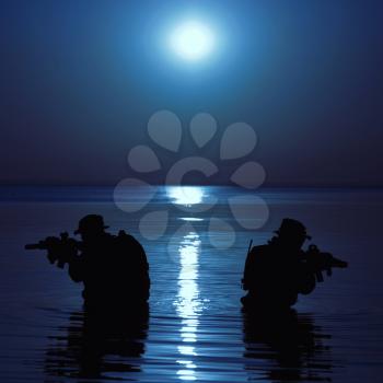 Army soldier with rifle night moon silhouette under cover of darkness in action during raid crossing river in the water. Covert diversionary operation
