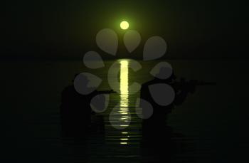Army soldier with rifle night moon silhouette under cover of darkness in action during raid crossing river in the water. Covert diversionary operation