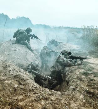 Squad of elite french paratroopers of 1st Marine Infantry Parachute Regiment RPIMA in action in enemy trenches filled with gunpowder smoke