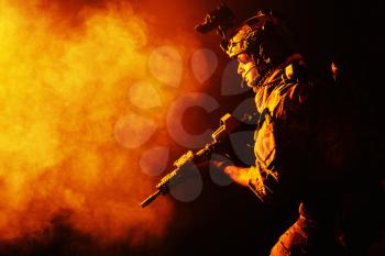 Security forces operator in Combat Uniforms with rifle, in the face of danger. Facing enemy, he is ready to fight. Studio contour silhouette shot, toned and colorized, backlight, profile side view