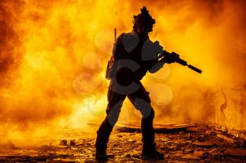 Black silhouettes of soldier in the smoke fire burning moving in battle operation. Back light