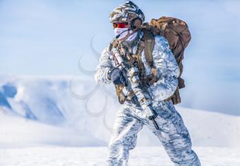 Army serviceman in winter camo somewhere in the Arctic. He wears chest rig, backpack, suffers from extreme cold, strong wind, but endures while mission continues, running moving across snow desert