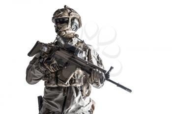 Army soldier in Protective Combat Uniform holding Special Operations Forces Combat Assault Rifle. Studio shot, dark contrast, cropped, desaturated, isolated on white background